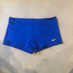 a pair of blue nike shorts laying on top of a white carpeted floor next to a bed