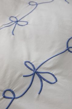 a white sheet with blue ribbon on it and an embroidered bow at the end of the line