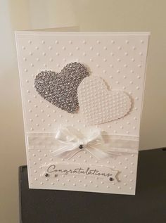 a card with two hearts on it and the words congratulations written in silver glitters