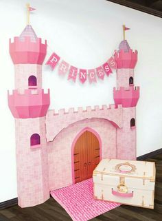 there is a pink princess castle set up on the floor next to a white suitcase