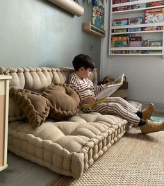 a young boy sitting on top of a couch reading a book