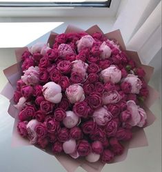 a bouquet of pink roses sitting on top of a table next to a windowsill