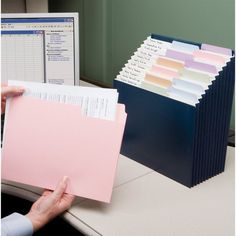 a person holding a folder in front of a computer