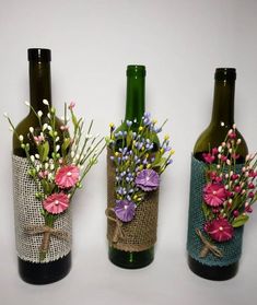 three wine bottles decorated with flowers and burlocks