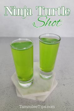 two glasses filled with green liquid sitting on top of a white plate next to the words ninja turtle shot