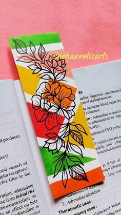 a bookmark with flowers on it sitting next to an open book