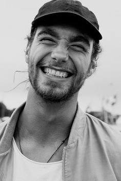 a black and white photo of a man with a hat on smiling at the camera