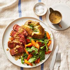 a white plate topped with meat and veggies next to a bowl of sauce