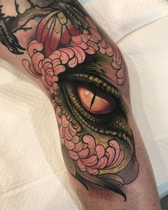 a close up of a person's leg with an eye and flowers on it