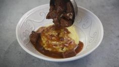 a white plate topped with meat and gravy covered in sauce on top of a table