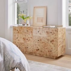 a bedroom with a bed, dresser and pictures on the window sill in it