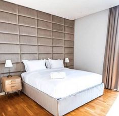 a bed with white sheets and pillows on top of it in a bedroom next to a window