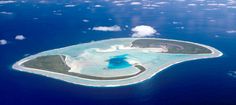 an island in the middle of the ocean surrounded by land and water with clouds above it