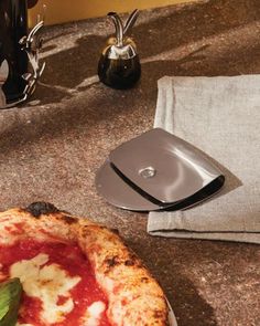 a pizza sitting on top of a table next to a silver plate and napkin holder