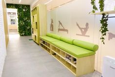 a green bench sitting in the middle of a room next to a wall with yoga images on it