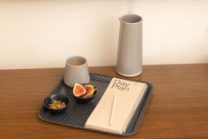 a wooden table topped with two cups and a plate filled with fruit on top of it