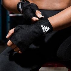 a close up of a person sitting down with their hands on the wrist and wearing black gloves