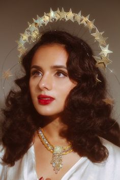 a woman wearing a tiara with gold stars on it's head and red lipstick