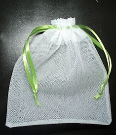 a small white bag with green ribbon on the top and bottom, sitting on a black surface