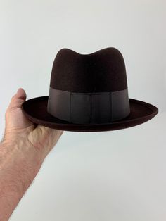 Vintage 1940'S-50'S chocolate brown wool felt fedora with a wide grosgrain ribbon band.  This is a ROYAL STETSON FEDORA manufactured by the John B Stetson Company on one side of the leather sweatband is printed: Melvin E. Beck Hub Clothing Co. Moorhead The other side is printed: ROYAL STETSON This fedora is in EXCELLENT VINTAGE CONDITION... with no signs of wear. This is in MINT CONDITION NOS DEADSTOCK The leather sweatband is perfect.. and the lining is beautiful with a satin checked fabric on the inside... SIZE: MEN'S SIZE 7-1/8 Measurements: Inside measure along the sweatband is approximately 22-1/2 inches Brim is 2-1/4 inches wide Stack is approximately 4-1/4 inches tall at the crease. The grosgrain ribbon band is  2 inches wide Stetson Fedora, Checked Fabric, John B, Felt Fedora, Check Fabric, Clothing Co, Grosgrain Ribbon, Chocolate Brown, Wool Felt