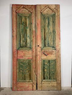 an old pair of wooden doors sitting on top of a white wall next to each other