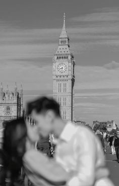 a man and woman standing in front of the big ben clock tower