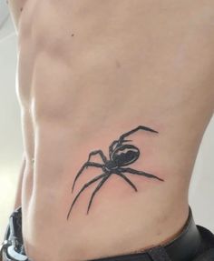 a black spider tattoo on the side of a man's rib - up stomach