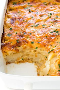 a casserole dish with cheese and parsley on top in a white dish