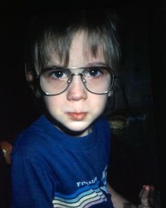 a young boy wearing glasses and looking at the camera