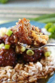 a spoon full of food on top of rice and broccoli with meat in sauce