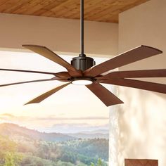 a ceiling fan that is hanging from the ceiling in front of a window with mountains behind it