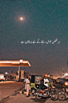 two people standing in front of a gas station at night with the sky lit up