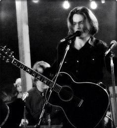 a man holding a guitar while standing in front of a microphone