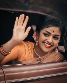 a woman is waving out the window of a car