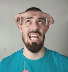 a man holding a donut in front of his face with one hand on the top of his head