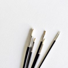 three pens sitting next to each other on a white surface