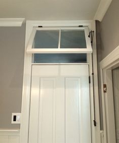 a white door with two glass panes on the top and bottom panel, in front of a gray wall