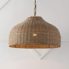 a woven light fixture hanging from a ceiling in a room with white walls and flooring