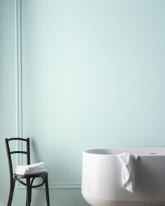 a chair sitting next to a bathtub in a room with blue walls and white flooring