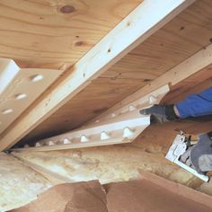 a man in blue jacket working on wooden beams