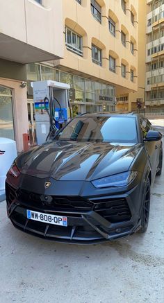 a black sports car is parked in front of a building with an open gas pump