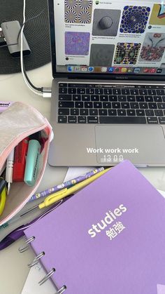 an open laptop computer sitting on top of a desk next to a notebook and pen