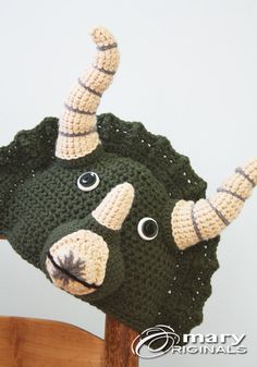 a crocheted stuffed animal hat with horns on it's head sitting on top of a wooden chair