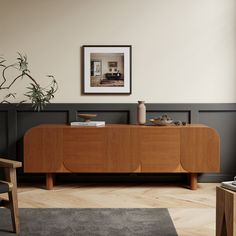 a living room with a large wooden cabinet next to a chair and potted plant