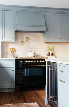 a black stove top oven sitting inside of a kitchen next to wooden floors and cabinets