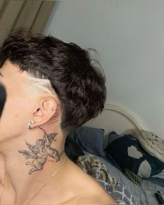 a woman with a tattoo on her neck and behind her ear is looking at the camera