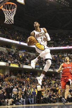 a basketball player jumping up into the air to dunk a ball in front of an audience