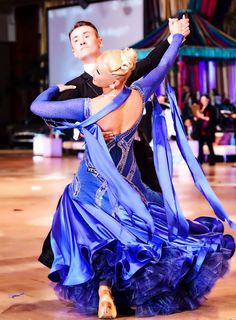 a man and woman dancing on a dance floor with blue ribbons around their ankless