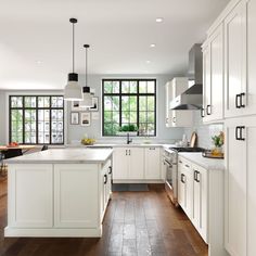 a large kitchen with white cabinets and wood floors