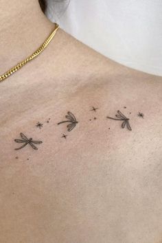 the back of a woman's shoulder with three dragonflies on it and stars in the sky